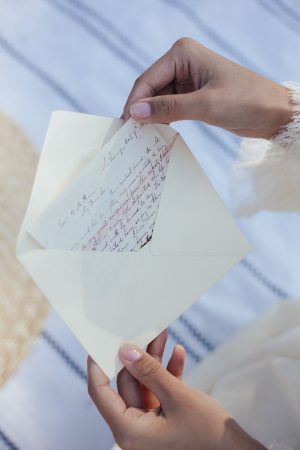 A woman's hands open an envelope containing a handwritten love letter, evoking nostalgia and romance.