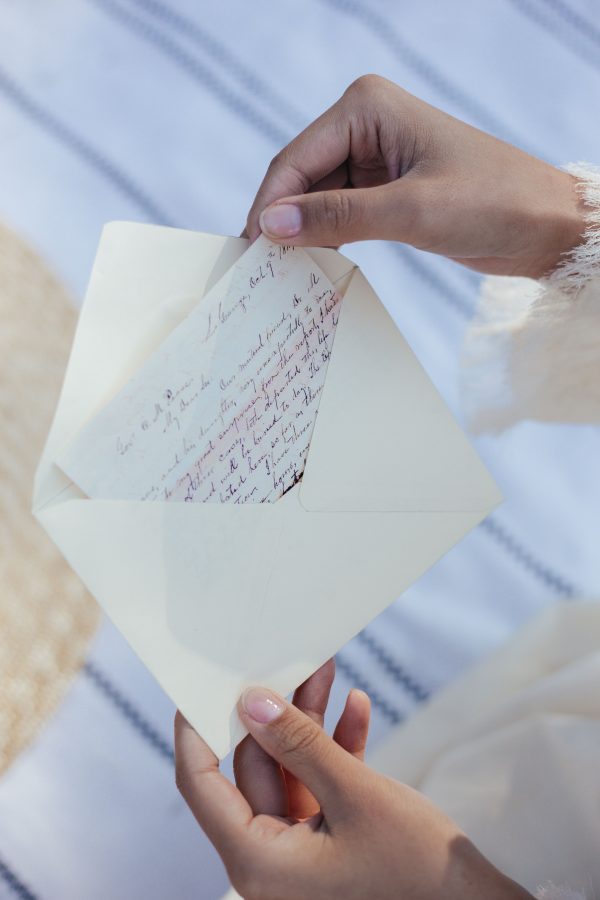 A woman's hands open an envelope containing a handwritten love letter, evoking nostalgia and romance.