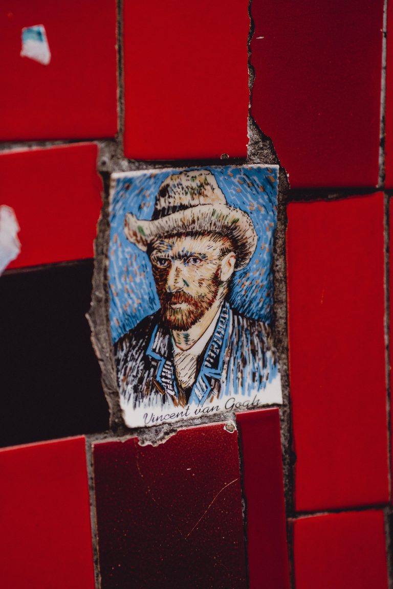 Close-up of Van Gogh portrait tile set among vibrant red bricks in Rio de Janeiro.